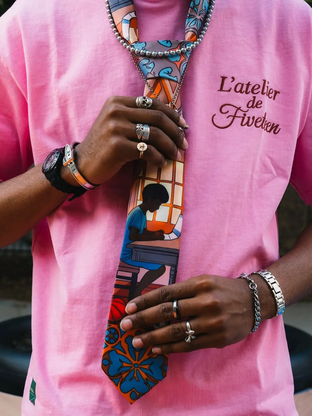 Pink L’atelier de Fiveteen tee with script chest logo, worn with a printed tie