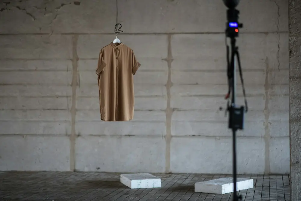 A brown coat hanging alone on a rail in a bare concrete studio