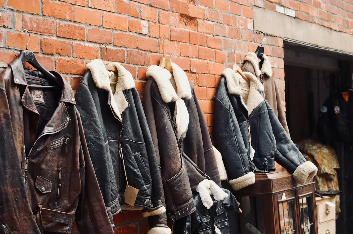 Four leather jackets with shearling collars hanging on a brick wall